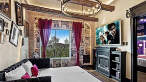 Un dormitorio con una cama grande, televisión, chimenea y pared de ladrillo.