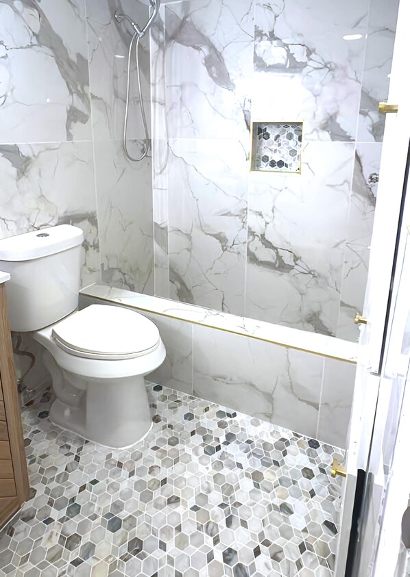 A bathroom with a toilet, shower, and tiled floor.