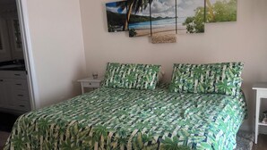 Un dormitorio con cama, ventilador de techo, mesita de noche y cuadros en la pared.