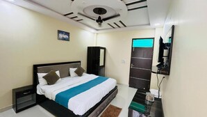 Une chambre moderne avec un lit, un miroir, une télévision et un ventilateur de plafond.