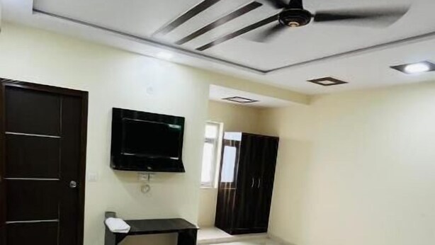 Une chambre d’hôtel équipée d’un lit, d’un téléviseur fixé au mur, d’un ventilateur de plafond et d’une armoire.