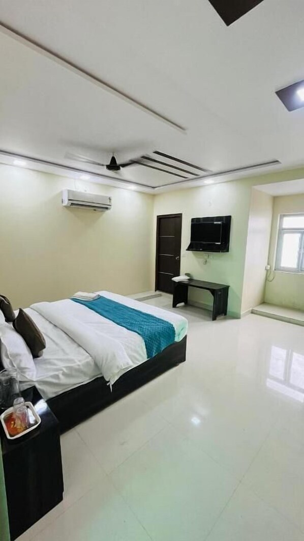 Habitación de hotel con cama, escritorio, aire acondicionado y televisor montado en la pared.