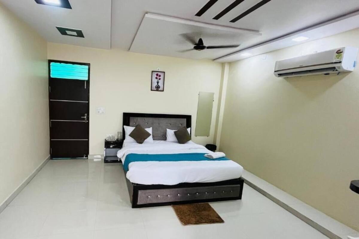 Een slaapkamer met een bed, nachtkastjes, een wandairconditioner en een plafondventilator.