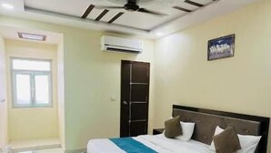 Une chambre d’hôtel équipée d’un lit, d’un bureau, d’une chaise, d’un ventilateur de plafond et d’un appareil de climatisation.