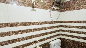 Une salle de bain équipée de toilettes, d’un lavabo et d’un sèche-mains fixé au mur.