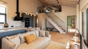 Un salon moderne comprenant un canapé, un coin repas et un escalier menant à un niveau supérieur.