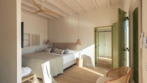Une chambre à coucher comprenant un lit, une table de chevet, une chaise et une porte donnant sur une autre pièce.