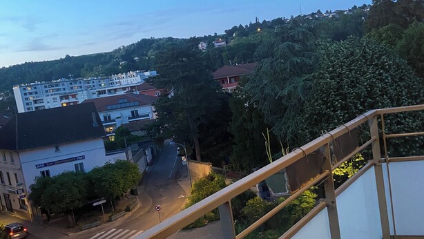 A balcony with a metal railing overlooking a street with buildings and trees. - Apartment 85m2 short term rental 1 month 2 months 3 months max available (Bourgoin-Jallieu)