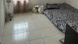 A small, sparsely furnished room with a bed, a desk, and a window with curtains. - Apartment 85m2 short term rental 1 month 2 months 3 months max available (Bourgoin-Jallieu)