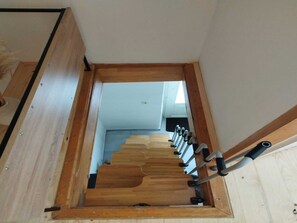 A wooden staircase with a handrail, leading to an upper floor.