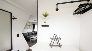 A modern, well-lit room with a white dresser, a black metal rack, and a potted plant on the wall. - Tiny house close to nature with barbecue area - pet-friendly & close to the lake (Lohmen)