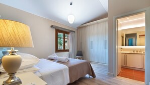 A hotel room with a bed, bedside table, lamp, and a view of the bathroom.