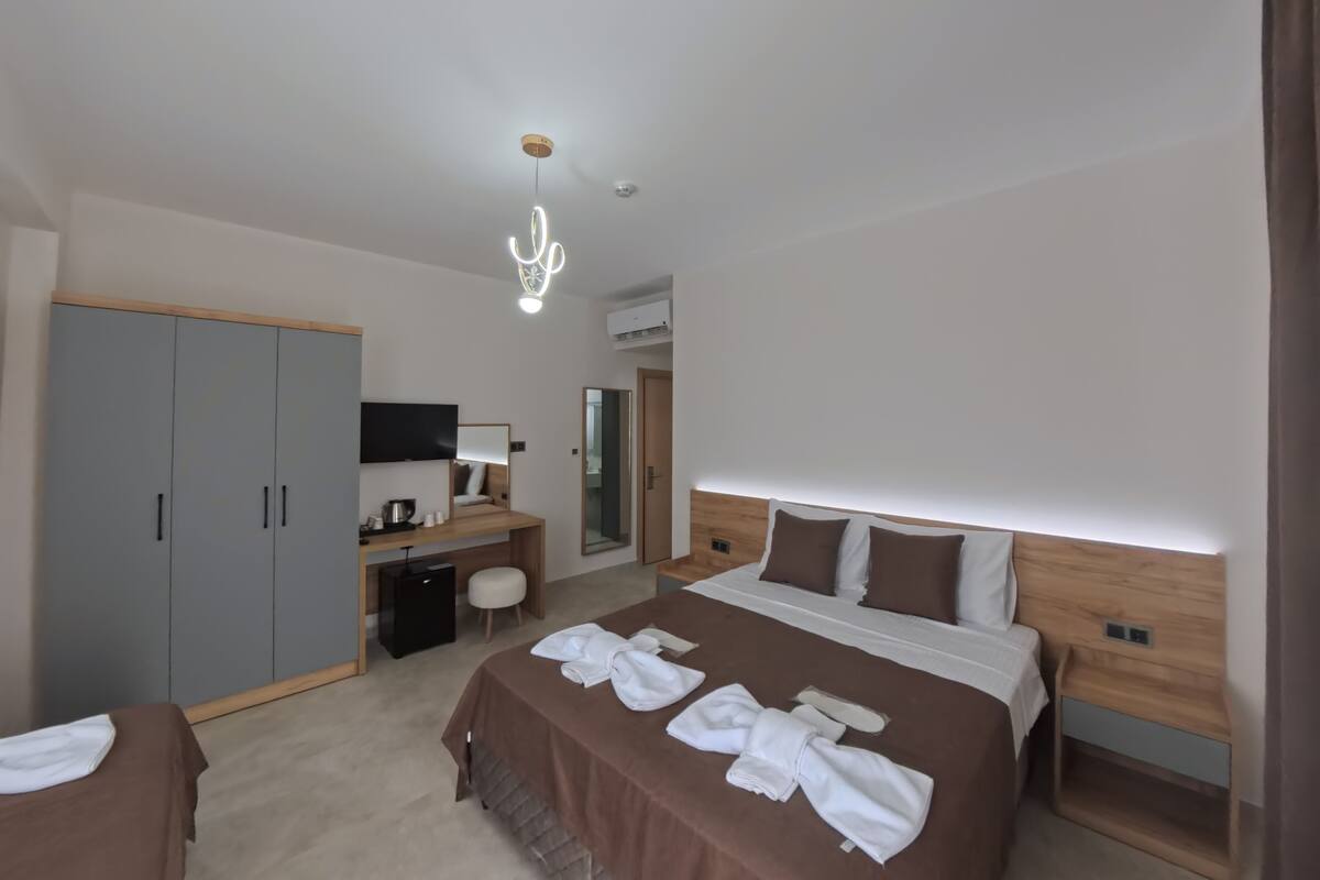 A hotel room with a large bed, a desk with a chair, a wardrobe, and a television.