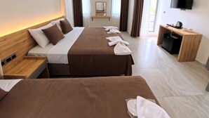 Une chambre d’hôtel avec deux lits, une télévision, un bureau avec une bouilloire et un miroir.