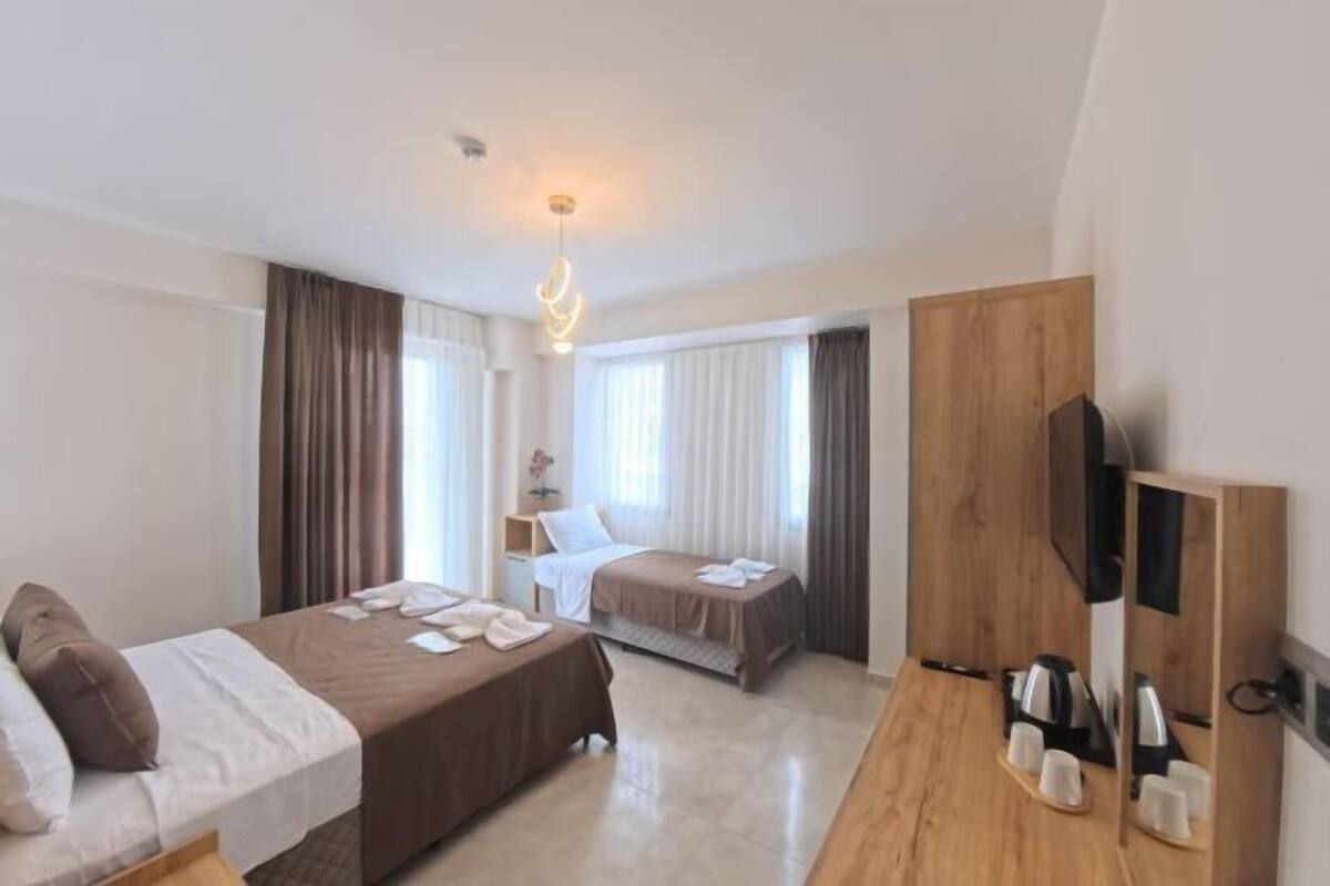 A hotel room with two beds, a wooden desk, a television, and a coffee maker.