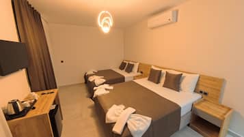 Een hotelkamer met een groot bed, een kleiner bed, een bureau met telefoon en een televisie.