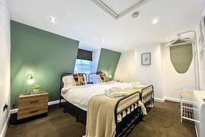 Relax in this serene bedroom with a double bed, nightstand, and a potted plant.