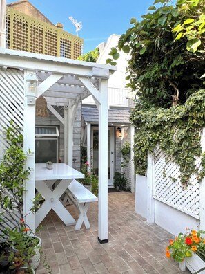 A covered patio area with a white pergola, a table, and potted plants.