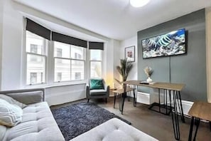 Enjoy the city view from the comfort of this stylish living room, featuring a sofa, table, and artwork.