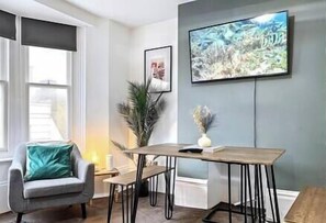 Relax in this stylish living room with a large flat-screen TV, dining table, and comfortable armchair.