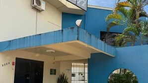 Un edificio con fachada azul, un letrero que dice "Hotel" y una planta en maceta en la entrada.