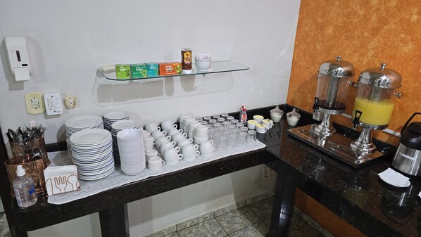 A buffet setup with plates, cups, and condiments. - BRAVO ADM FILIAL 8 NOVA MUTUM (Nova Mutum)