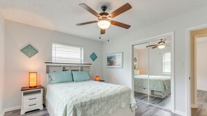 Una camera da letto con un letto, comodini, una ventola a soffitto e un grande specchio.