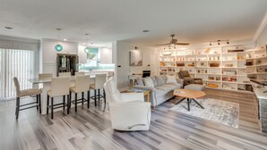 Un soggiorno moderno con angolo pranzo, divano, tavolino e libreria piena di libri e oggetti decorativi.