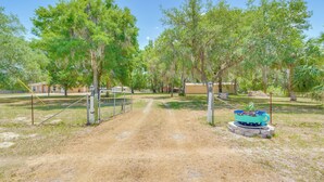 A dirt path leading through a fenced area with trees and a decorative planter. - < 1 Mi to Lake Rousseau: Waterfront Home! (Inglis)