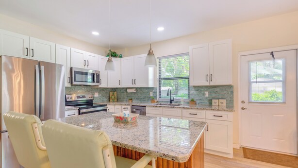 A modern kitchen with white cabinets, stainless steel appliances, a wooden island, and pendant lighting. - < 1 Mi to Lake Rousseau: Waterfront Home! (Inglis)