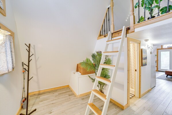 A staircase with a wooden handrail and a white wall with a small white cabinet. - Cozy Cabin w/ Fire Pit: Walk to Lake Taneycomo! (Rockaway Beach)