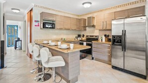A modern kitchen with a central island, stainless steel appliances, and a breakfast bar. - Palma Real 60 (Noord)