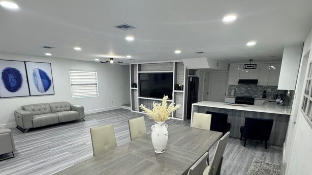 A modern living room with a dining area, a kitchen, and a seating area with a sofa.