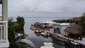 A marina with boats docked, a thatched-roof building, and a small house with a balcony.