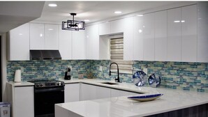 A modern kitchen with white cabinetry, a central island, and a patterned backsplash.