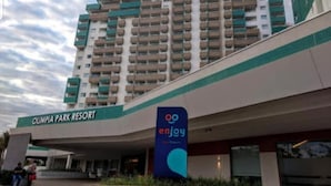 Un hotel de varios pisos con un letrero que dice "Olympia Park Resort" y un logotipo de "enjoy".