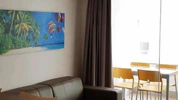 A modern living room with a brown leather sofa, a wooden coffee table, and a painting of hot air balloons.