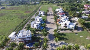 Et resort med flere hvide bygninger, en sandstrand og palmer.