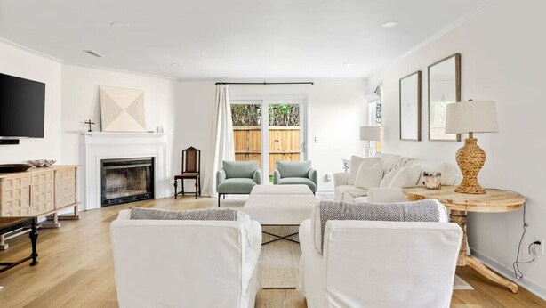 A spacious living room with a fireplace, a television, and a view of the outdoors through a large window. - Renovated! Coastal 3 Bedroom in the Heart of MTP (Mount Pleasant)