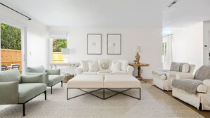 A spacious living room with a large sofa set, a coffee table, and a view of the outdoors. - Renovated! Coastal 3 Bedroom in the Heart of MTP (Mount Pleasant)