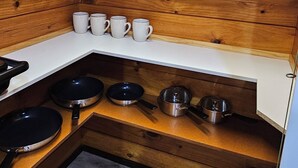 A compact kitchen with wooden walls, white countertops, and a built-in stove. - Experience nature at it's finest! (Pukekohe)