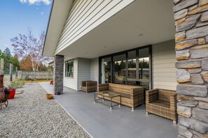 A covered patio area with wicker furniture, stone pillars, and a view of the surrounding landscape.