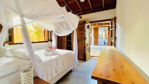 A bedroom with a four-poster bed, wooden furniture, and a view of the outside. - Casa da Primavera (Porto Seguro)