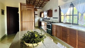 A kitchen with wooden cabinets, a stove, and a sink. - Casa da Primavera (Porto Seguro)