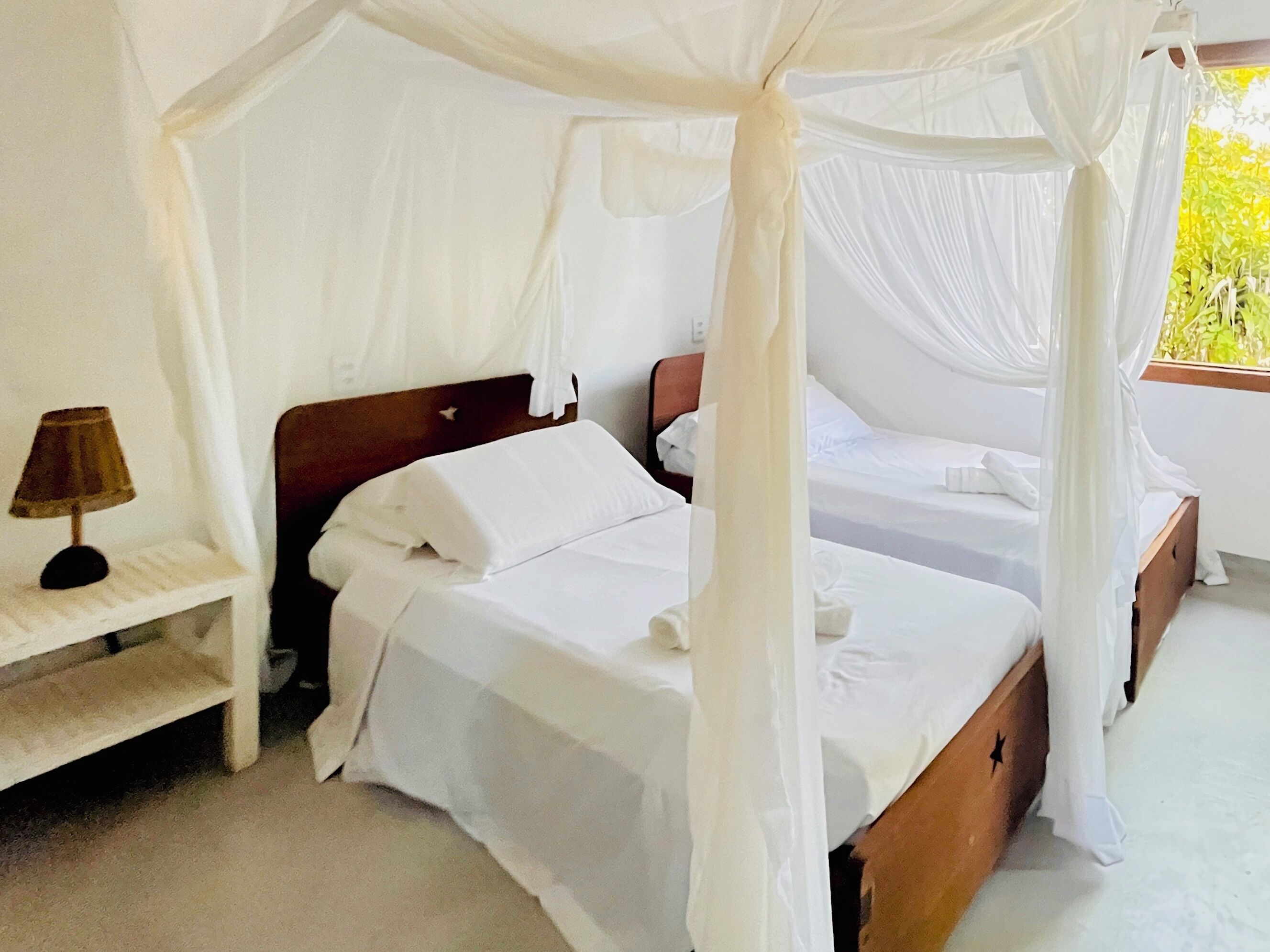 A room with a canopy bed, a bedside table, and a lamp.