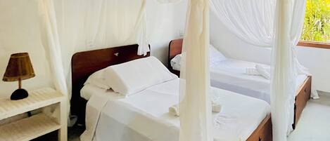 A room with a canopy bed, a bedside table, and a lamp.