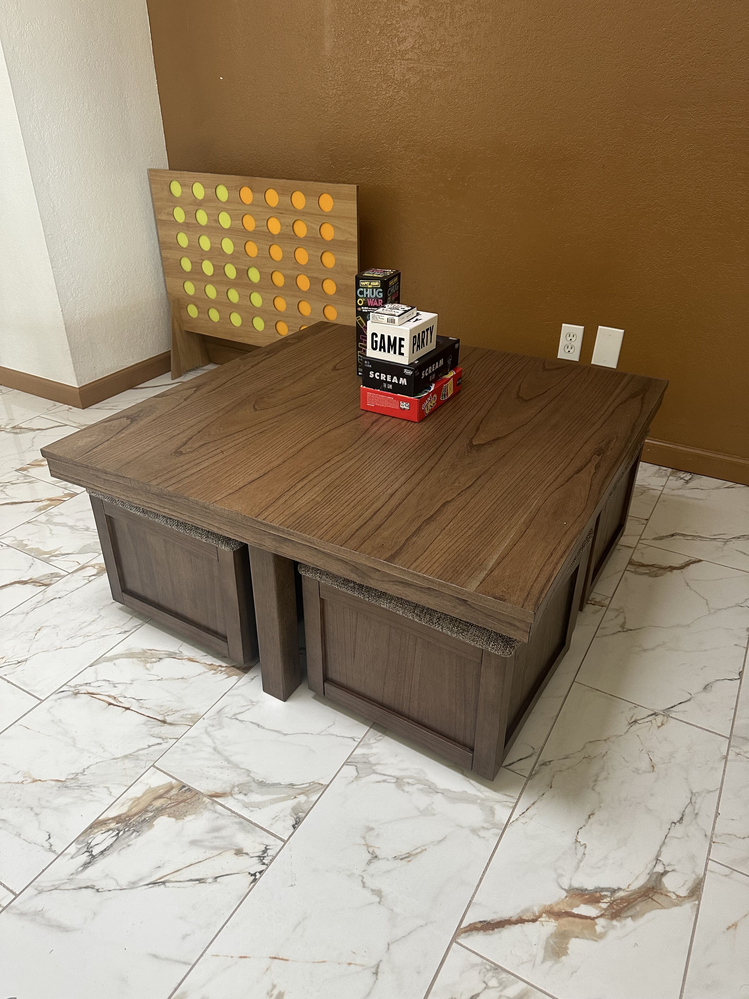 A wooden table with a stack of game boxes on top.