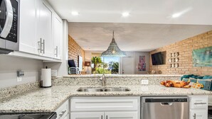 A modern kitchen with granite countertops, stainless steel appliances, and a brick accent wall. - Condo in Beachfront Community! 4th nt FREE! (Port Aransas)
