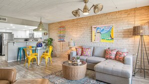 A modern living room with a gray sofa, a coffee table, and a dining area with yellow chairs. - Condo in Beachfront Community! 4th nt FREE! (Port Aransas)