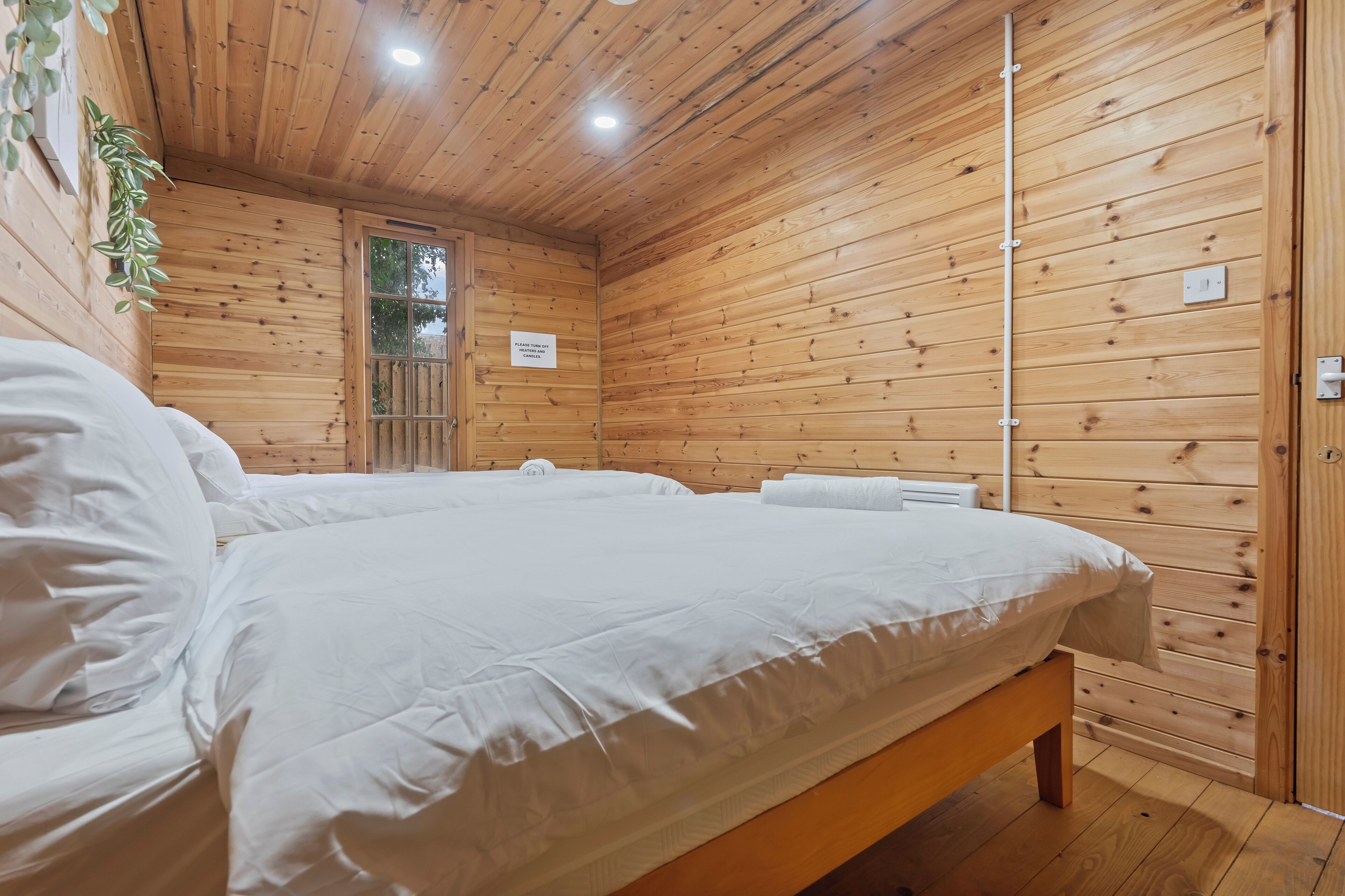 Una habitación con paneles de madera, una cama grande, un banco de madera y una pequeña mesa.